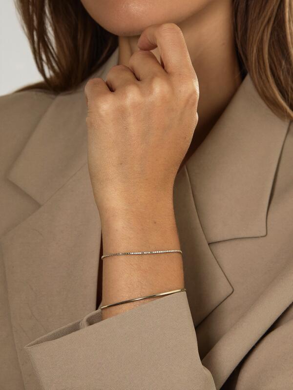 Model wearing a tennis bracelet and slim bangle