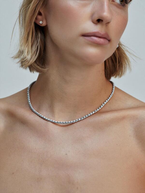 Model wearing a silver-tone necklace and studs